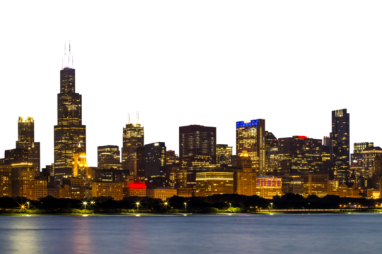 Chicago skyline at dusk, featuring illuminated buildings against a twilight sky, shot from a distance with water in the foreground