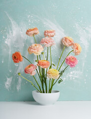 close-up of a bouquet of pale pink and orange ranunculus on a blue background