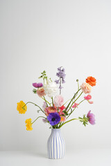A colorful bouquet of fresh flowers in a striped vase on a white background. A mix of summer colored flowers, a bouquet for a holiday