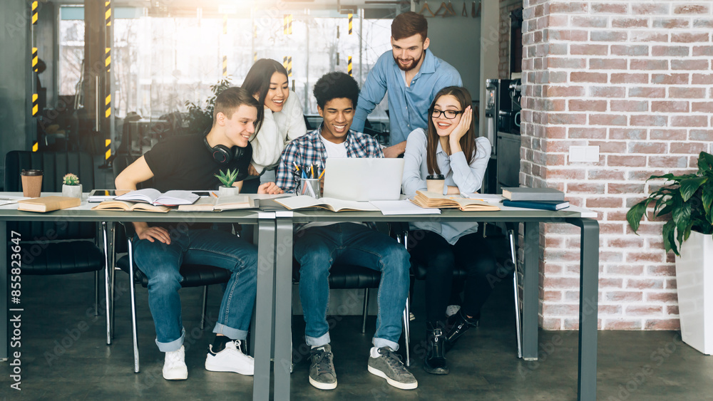 Poster A group of diverse students are seated around a large conference table in a modern library. They appear engaged in a meeting or discussion, with papers and laptops scattered around the table.