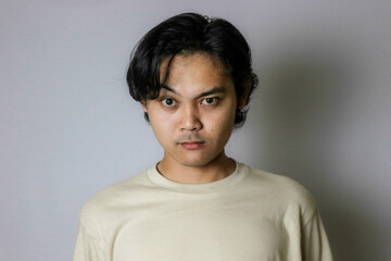 Portrait of an Asian Indonesian young man wearing a white shirt with a random expression when photographed with an isolated white background