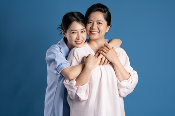 Image of an Asian mother and child posing on a blue background.