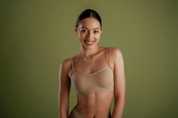 Smiling, cheerful facial expression. Woman with slim body shape is posing against background