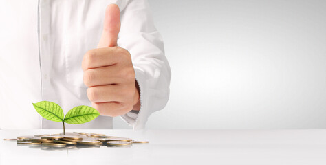 Businessman holding plant sprouting from a handful of coins