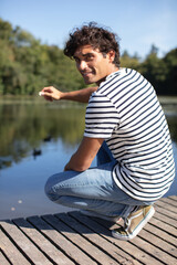 young happy man feeding ducks in the pond