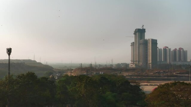 A wide shot of the smog-filled urban landscape with newly constructed buildings, skyscrapers or residential complexes to cater ever expanding city needs. Concept of Air pollution and development
