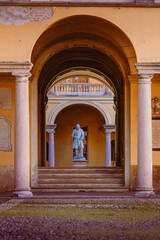 Fototapeta premium Statue inside the courtyard of the University of Pavia through the various porticos