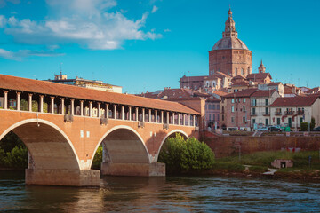 Obraz premium Pavia's Ponte Vecchio with historic city center and Duomo behind, blue sky with white clouds, vertical