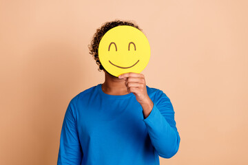 Photo of cheerful positive guy wear trendy blue clothes hold yellow smiley isolated on beige color...
