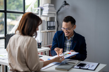 A man and a woman are sitting at a desk with a presentation in front of them