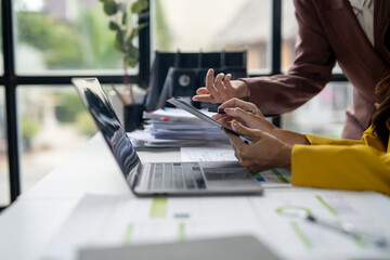Two people are working on a laptop and tablet