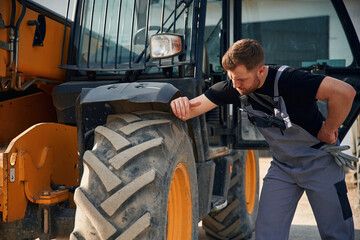 Checking the wheel. Man is with tractor. Agricultural worker