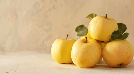 Selective focus image of golden delicious apples on a light beige backdrop with room for text