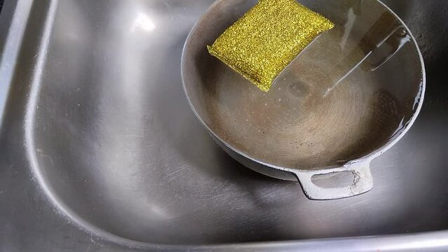 Una esponja amarilla flotando y movi&eacute;ndose en un caldero lleno agua en un fregadero