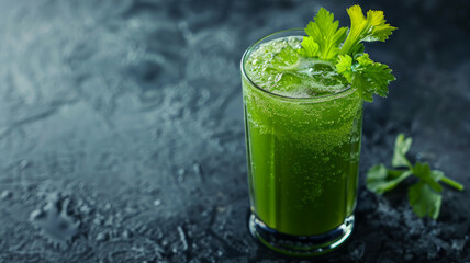 A green smoothie with celery garnish in a glass on a dark surface.