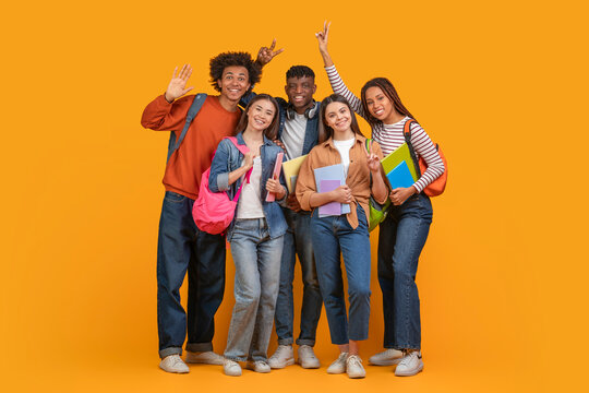 This image shows a group of diverse students smiling and posing together in front of a bright yellow background. They are all holding books and wearing backpacks