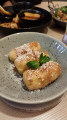 Caramel fried bananas topped with desiccated coconut on a plate in a restaurant with a select focus