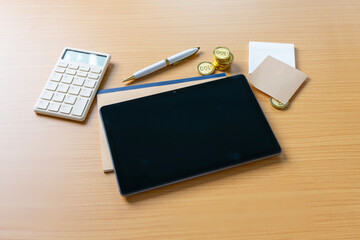 Financial objects - Blank digital tablet screen and coins on wooden background still life.