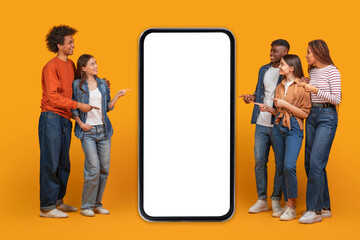 A group of five friends stand in front of a large smartphone with a blank white screen. They are...