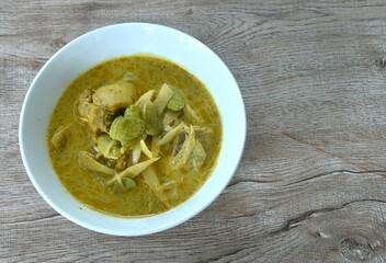 spicy boiled slice fresh bamboo shoot with chicken topping stink bean in coconut milk curry soup on bowl