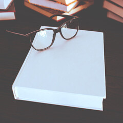 Book with space for text and black glasses on wooden table next to books