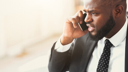 Got bad news. Close up of angry african businessman talking by phone with partners, panorama with copy space