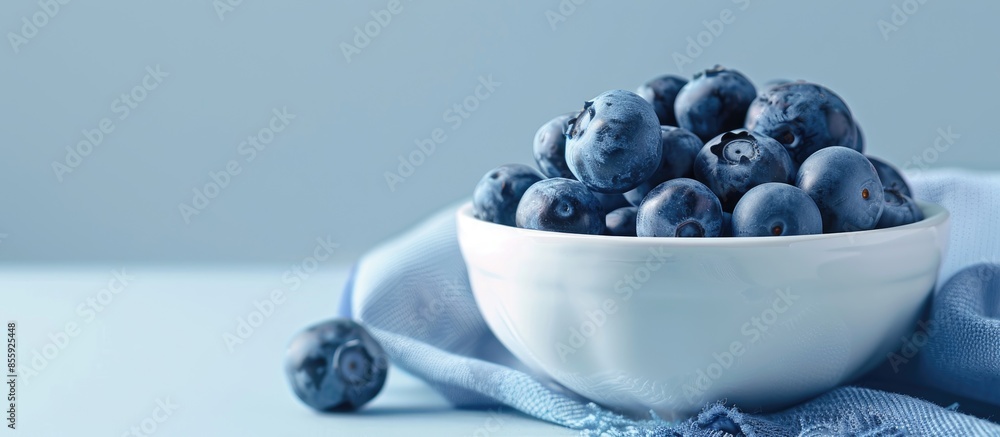 Poster closeup of blueberries in white porcelain bowl with blue napkin isolated on pastel background. shall