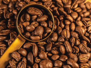 Coffee beans with gold measuring spoon on linen texture background	
