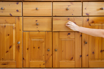 Background of old wooden chest of drawers and woman's hand pulling a handle