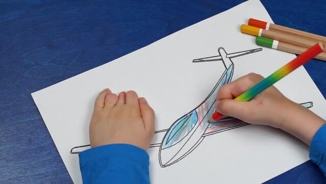 Сhild's hands with amniotic band syndrome colours a colouring book with pencils