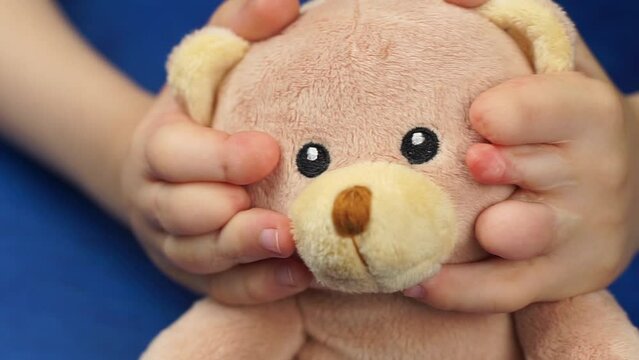 Child's hands after plastic surgery holding teddy bear head. Plastic surgery after finger separation with syndactyly.