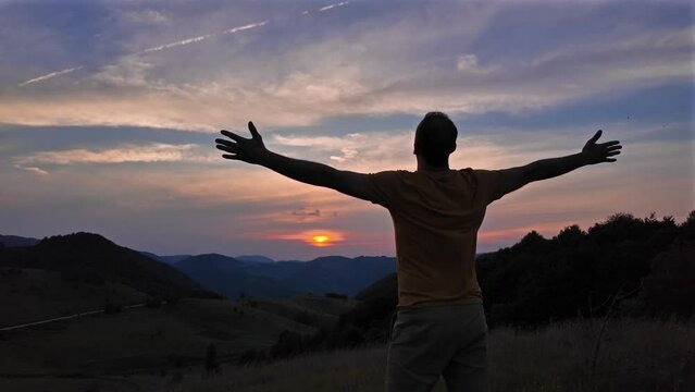 Silhouette of a man with arms wide open in nature.	

