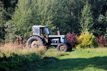 Old blue Russian agricultural tractors in the field. Agricultural machinery in the farm. Forest background