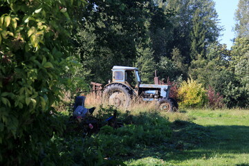 Old blue Russian agricultural tractors in the field. Agricultural machinery in the farm. Forest background