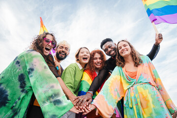 Group of LGBT young people stacking hands on a a gay pride parade. Community of homosexual,...