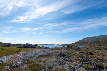 Greenland Nanortalik small lake landscape surrounded by volcanic lava stones and mountains on a sunny day