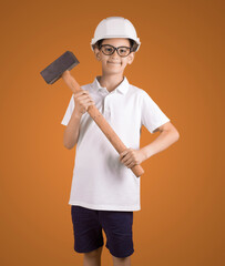 studio portrait of a Hindu boy worker in a hard hat with a hammeron a brown background . My future profession concept