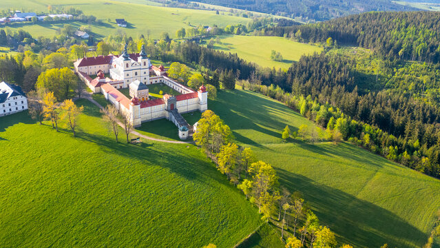 Aerial view of Hora Matky Bozi Monastery, located in Dolni Hedec near Kraliky, Czechia. The monastery is situated on a hilltop surrounded by lush green fields and forests. Aerial drone photography.