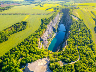 The breathtaking aerial view captures the lush green surroundings and turquoise waters of the abandoned Velka Amerika limestone quarry on a sunny summer day. Morina, near Prague, Czechia