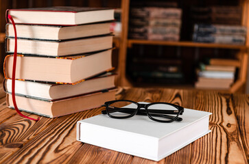 Black glasses lying on a white book next to old books
