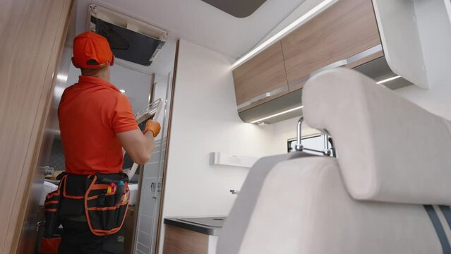 Worker Performing Camper Van Air Conditioning Unit Maintenance.