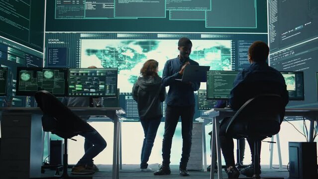 Governmental hackers performing a cyber attack simulation after studying the national database servers. Experts working on IT security, data breach prevention against ransomware. Camera B.