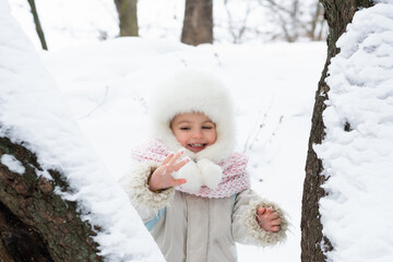 A cute baby in a snowy winter forest. Little girl having fun on winter day. Happy child in winter park