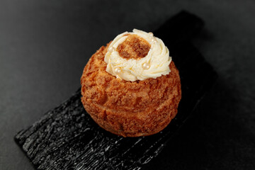 Classic Shu cake (choux). Custard dough based on butter and milk, classic custard filling with added cream on a black cutting board