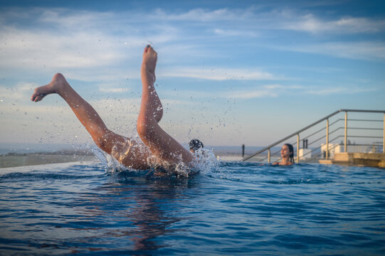 Side view of young woman jumping towards inflatable inside backyard swimming pool 1