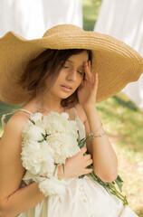 laundry day.barefoot woman walking on grass,holding white peonies in old rusted watering can,wearing sun beach hat.girl in dress against clothesline with bed sheets.vintage style,female relax on chair