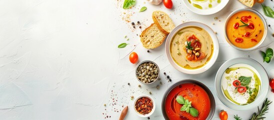 Flat-lay of creamy homemade soup in plates with bread slices over white plain table background, top view, copy space. Autumn Winter creamy vegan soups, vegetarian food menu, comfort food concept