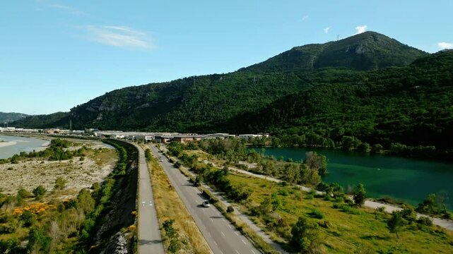 Drone footage of vehicles driving on Iscles road along Broc Lake on a sunny day in Le Broc, France