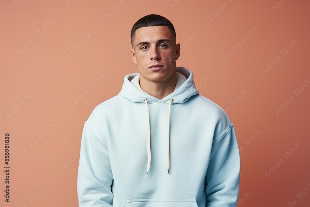 Wall mural a man wearing a blue hoodie is standing in front of a pink background