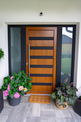 Entrance of a modern house gray wooden door white walls and flower pots with plants